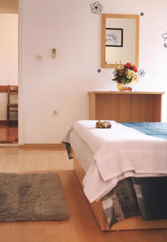 a bedroom with a bed with a vase of flowers on it at Apartment & Rooms Marigold in Baška Voda