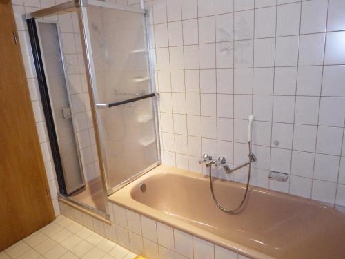 La salle de bains est pourvue d'une baignoire et d'une douche avec une porte en verre. dans l'établissement nette Ferienwohnung im Grünen, à Idstein