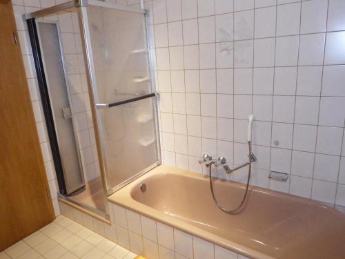 e bagno con vasca e doccia con porta in vetro. di nette Ferienwohnung mit eigenem Eingang und Sonnenterrasse a Idstein
