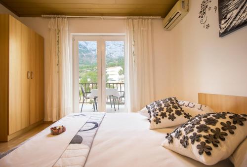 1 dormitorio con cama con almohadas y ventana en Apartment & Rooms Marigold, en Baška Voda