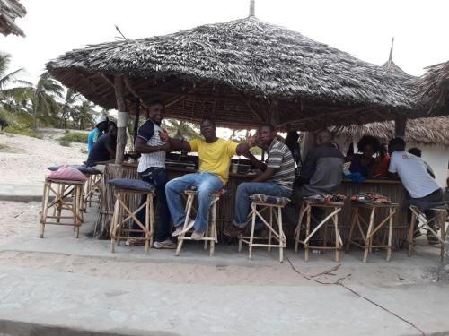a group of men sitting at a bar under an umbrella at Mambrui Golden Beach Bar and Cottages in Mambrui