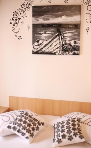 a bed with two pillows and a picture on the wall at Apartment & Rooms Marigold in Baška Voda