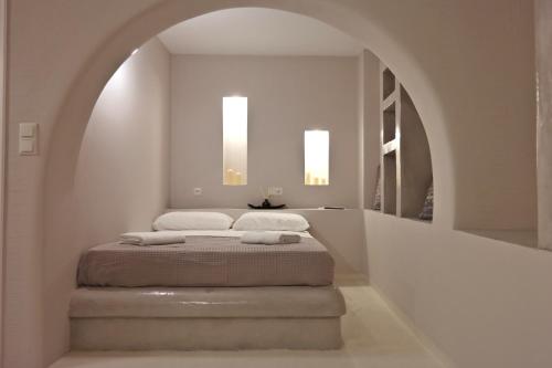 a bed in a white room with an archway at Sahara Apartments in Kastraki Naxou