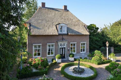 a house with a thatched roof and a garden at De Oude Pastorie Macharen in Macharen