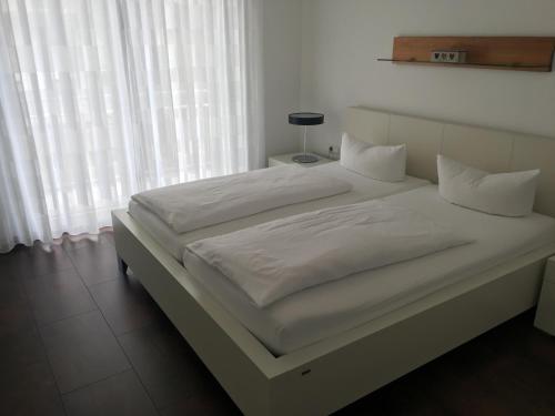 a large white bed with white sheets and pillows at Golf Appartement 2.11 Hebelhof in Bad Bellingen