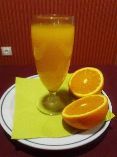 un vaso de zumo de naranja y dos naranjas en un plato en Hotel Romero Merida, en Mérida