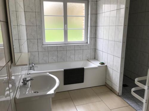 a white bathroom with a tub and a window at le clos du caribou in Beaumont-Hamel