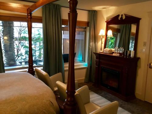 um quarto com uma cama, uma lareira e um espelho em The Tuwanek Hotel and Spa em Sechelt