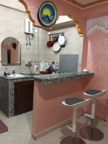 cocina con fregadero y encimera con taburetes en Stay Studio Apartment, en Rabat
