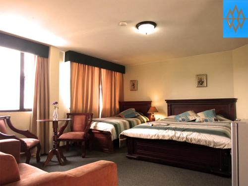 キトにあるAltura Rooms & Suitesのホテルルーム ベッド2台&椅子付