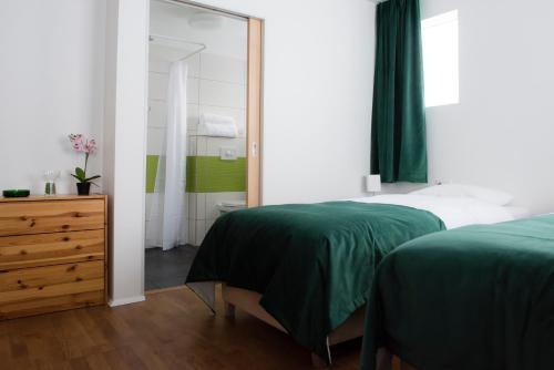 a bedroom with two beds and a mirror and a dresser at Media Luna Guesthouse in Seyðisfjörður