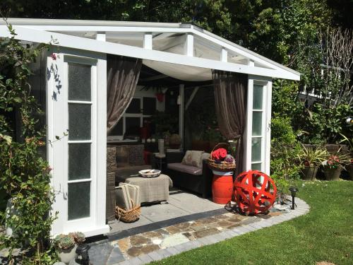 a white pergola with a couch in a garden at Ah House City B&B Nelson in Nelson