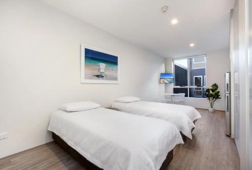 two beds in a room with white walls and a window at Bondi Beach Studio King Suite 1 in Sydney