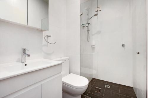 a white bathroom with a toilet and a shower at Bondi Beach Studio King Suite 1 in Sydney