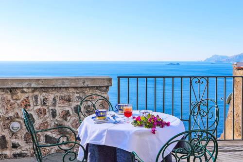 a table with drinks and flowers on a balcony at Villa Il Frantoio and Lilmar in Praiano
