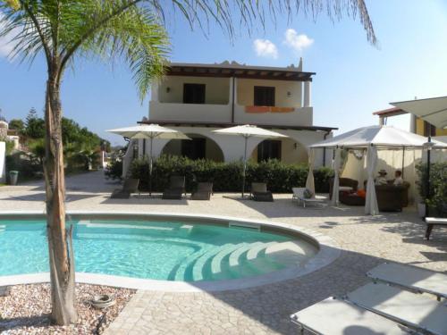 una piscina con una palma e una casa di Hotel Borgo Eolie a Città di Lipari