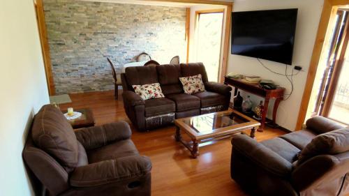 sala de estar con muebles de cuero y pared de ladrillo en Hospedaje Las Animas Valdivia, en Valdivia