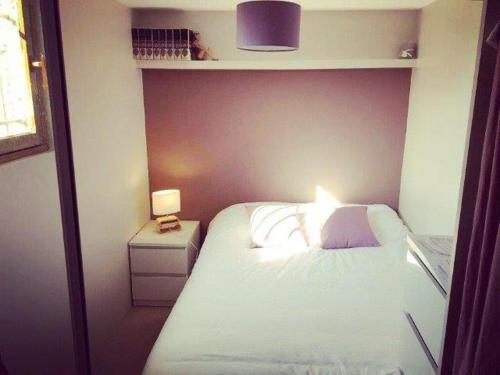 ein kleines Schlafzimmer mit einem weißen Bett und einer Lampe in der Unterkunft Les Libellules in Les Sables-dʼOlonne