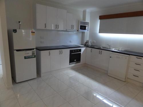 a kitchen with white cabinets and a white refrigerator at The Gums Anchorage in Bellara
