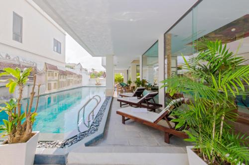 an outdoor patio of a hotel with a swimming pool at Ally Beach Boutique Hotel Hoian in Hoi An