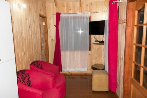 a living room with a red chair and a television at Cabañas Los Canelos Pucon, Hermosa Granja de 20 hectaréas a orillas del Río Liucura in Pucón