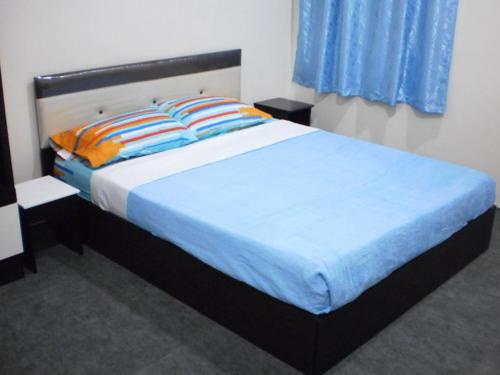 sypialnia z łóżkiem z niebieską pościelą i pomarańczowymi poduszkami w obiekcie Kerteh Inn w Kerteh