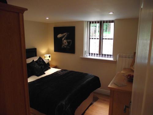 a bedroom with a black bed and a window at Carpenters Cottages in Llanishen