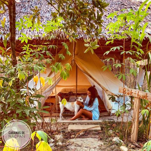 a woman sitting in a tent with a dog at Cabanas de Nacpan Camping Resort in El Nido