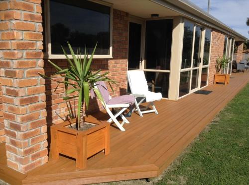 a wooden deck with two chairs and a potted plant at Darfield Bel Air right on the main street in Darfield