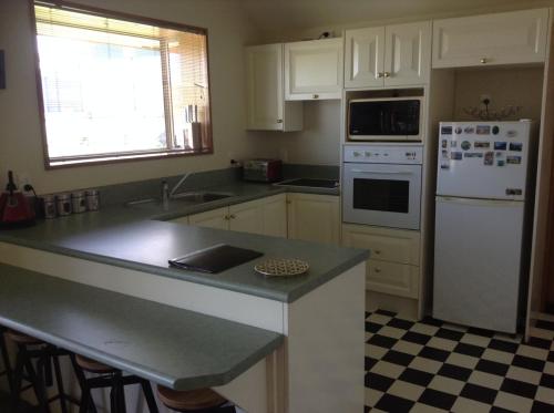 a kitchen with white appliances and a black and white checkered floor at Darfield Bel Air right on the main street in Darfield