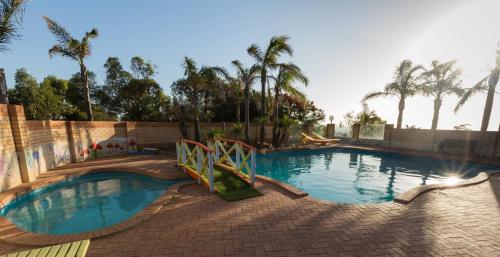 una grande piscina in un cortile con palme di Drummond Cove Holiday Park a Drummond Cove