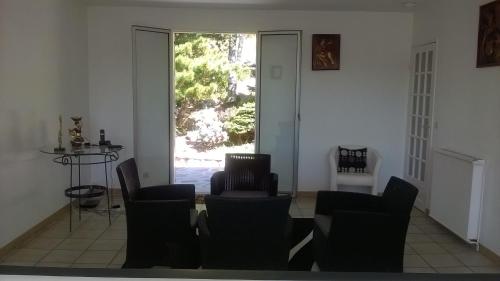 uma sala de estar com cadeiras e uma porta aberta em Maison trigueres em Triguères