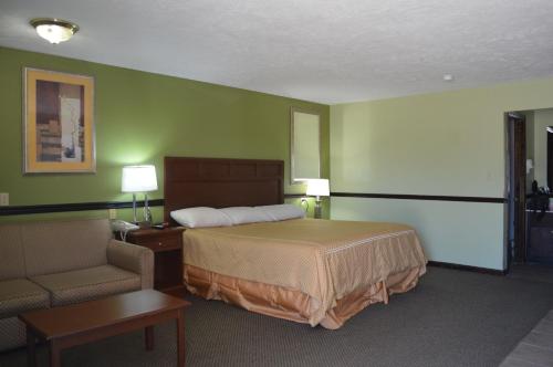 Habitación de hotel con cama y silla en Americana Inn - Henderson, en Henderson