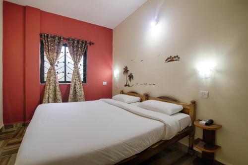 a bedroom with a large bed with red walls at Palm Shades Spring in Benaulim