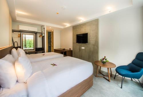 a hotel room with two beds and a chair at Dewa Phuket Resort & Villas, Nai Yang Beach in Nai Yang Beach