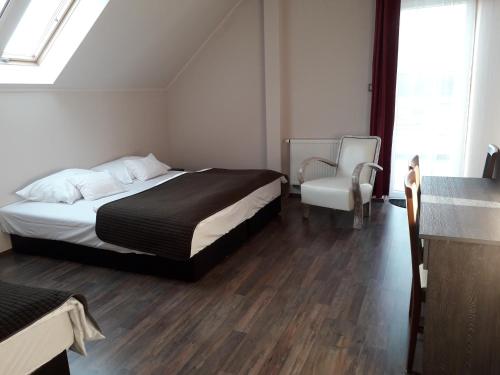 a bedroom with a bed and a chair at Caballus Lovasmajor Panzió in Nyíregyháza