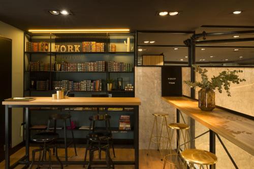 um bar com bancos e uma prateleira com livros em Petit Palace Alcalá em Madri