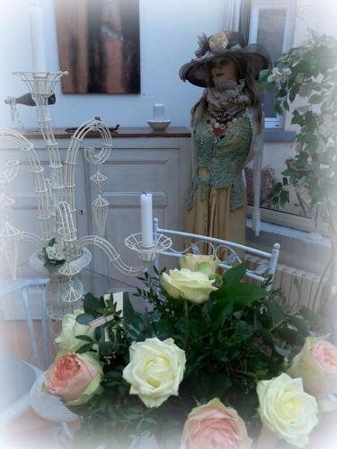 a woman is standing next to a table with roses at La Maison d'Hocquincourt in Bléneau