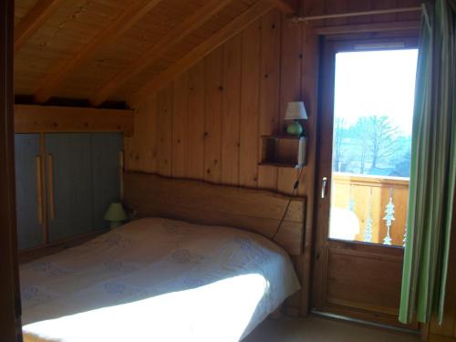 niewielka sypialnia z łóżkiem i oknem w obiekcie CHALET du DROPT w mieście Girmont-Val-dʼAjol