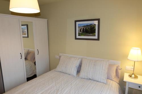 - une chambre dotée d'un lit blanc avec une photo sur le mur dans l'établissement Apartaments Sant Miquel, à Sant Joan de les Abadesses