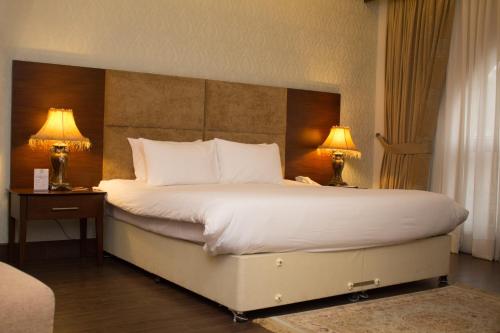 a bedroom with a large white bed with two lamps at S Chalet Islamabad in Islamabad