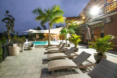 a row of lounge chairs next to a building with a pool at Phong Nha Lake House Resort in Phong Nha