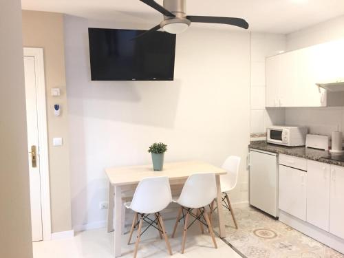 a kitchen with a table and chairs with a tv on the wall at Apartamentos Las Vegas in Ribadesella