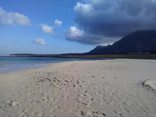 a beach with footprints in the sand and the water at Catarin Comfort Rooms in Castelluzzo