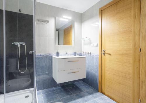 a bathroom with a white sink and a shower at 1- Apartamento Playa Canido in Malpica