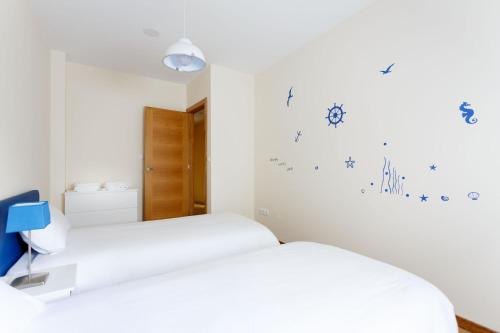 a bedroom with two beds and blue writing on the wall at 1- Apartamento Playa Canido in Malpica