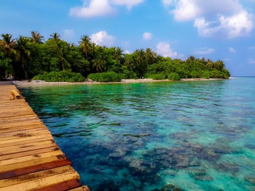 an island in the ocean next to a wooden pier at Nemo Inn in Omadhoo