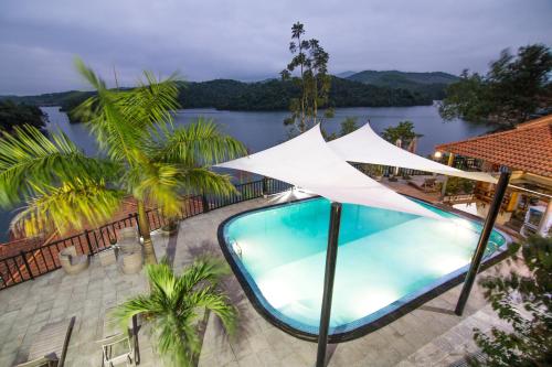 a swimming pool with a white umbrella next to a river at Phong Nha Lake House Resort in Phong Nha