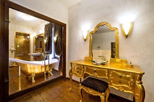 a gold bathroom with a tub and a sink at Arcadie Hotel & Apartments in Český Krumlov