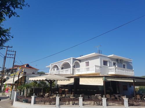 a white building with a balcony and tables and chairs at Mojo modern apartment in Alikanas